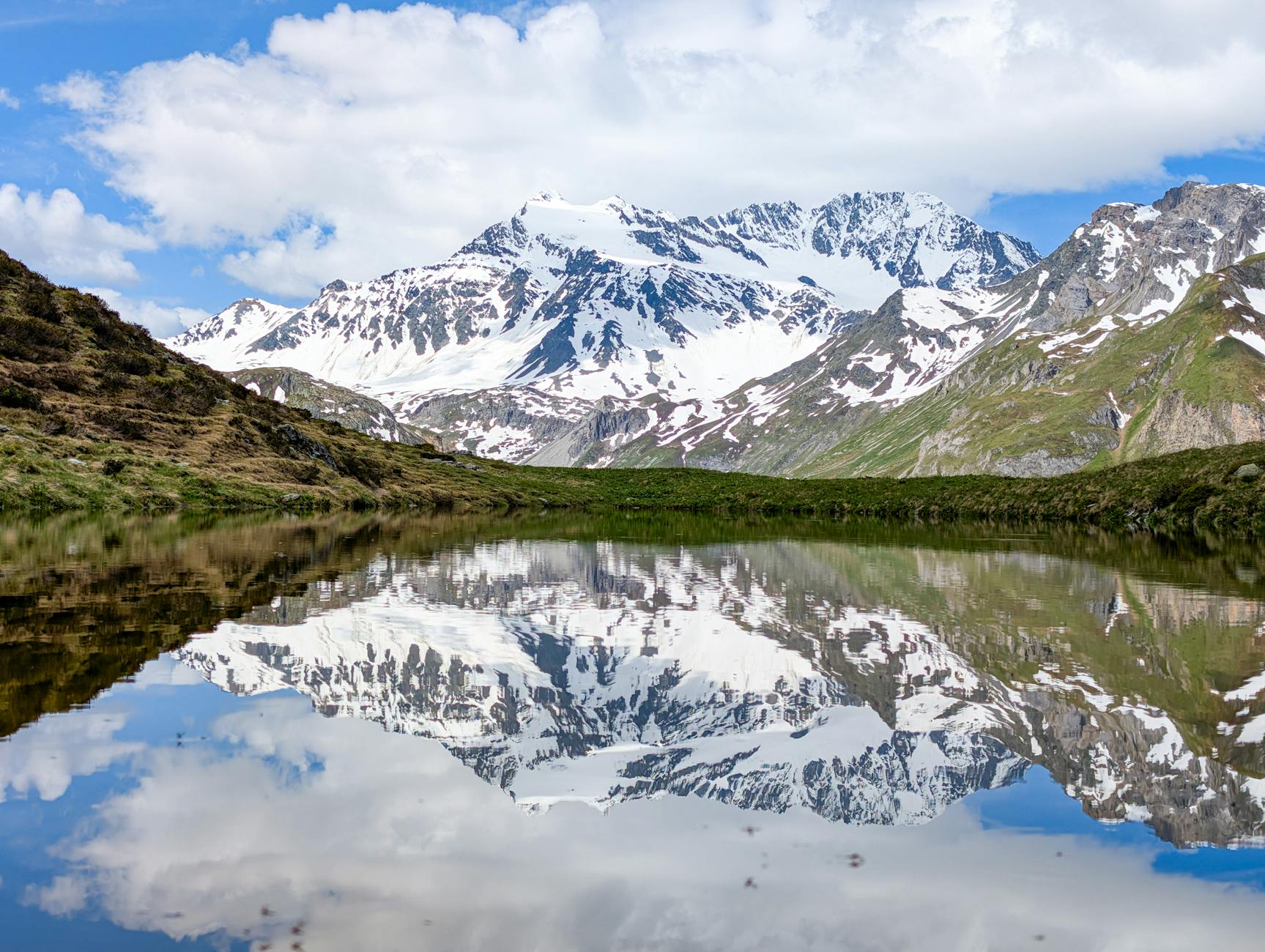 Lago alpino con riflessi delle montagne circostanti